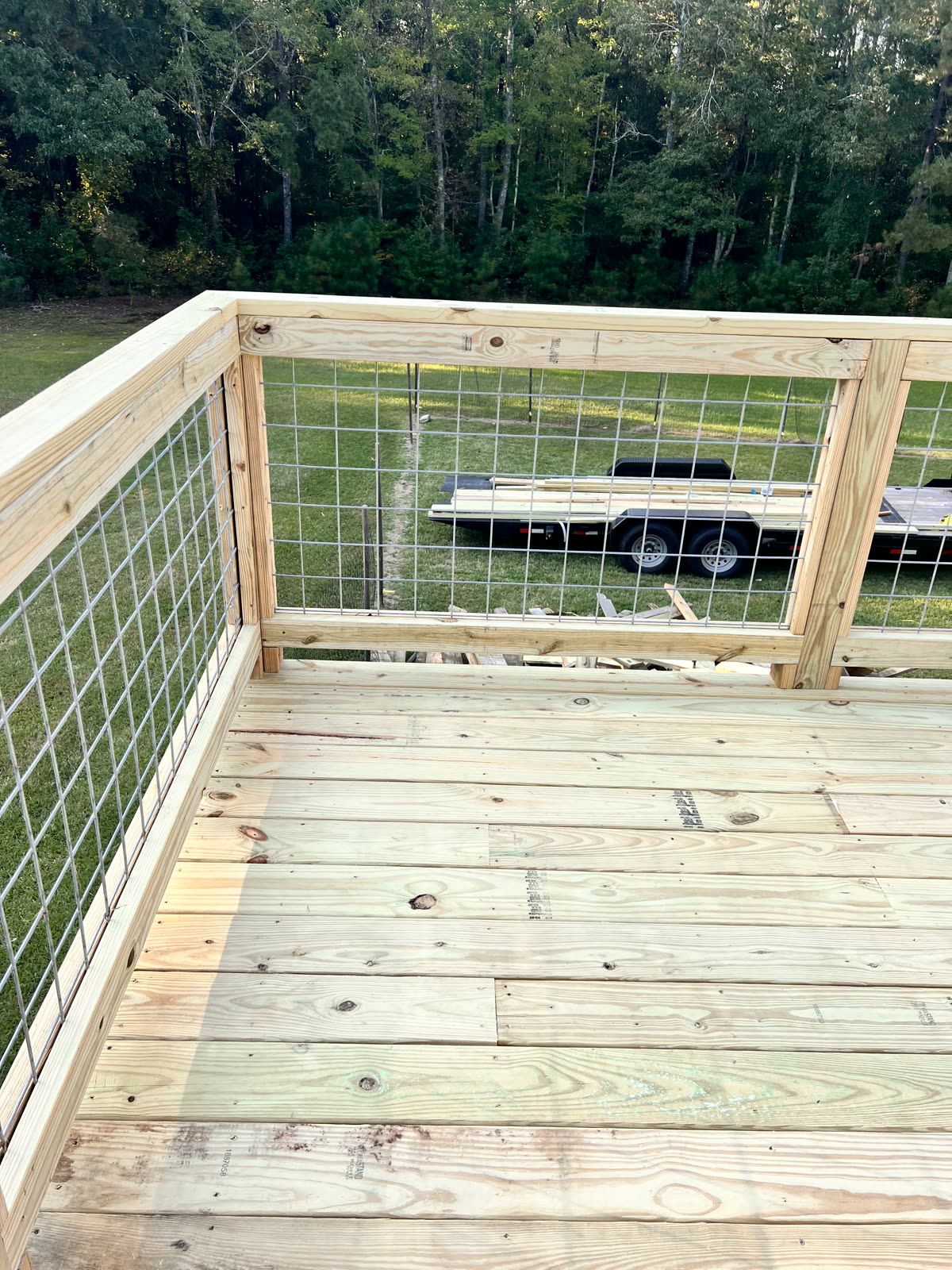 Newly constructed wooden deck with wire railing by Caballero C&L Remodeling