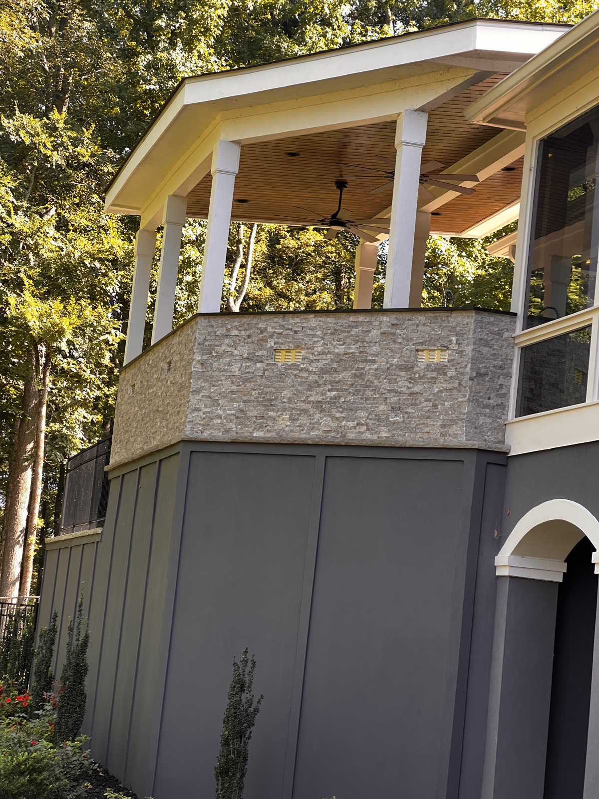 Elegant elevated porch with stone exterior and wood ceiling by Caballero C&L Remodeling