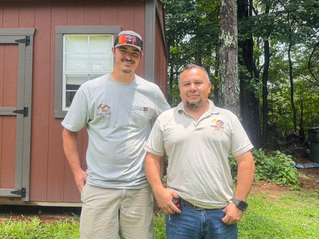 Team members in front of wooden outbuilding